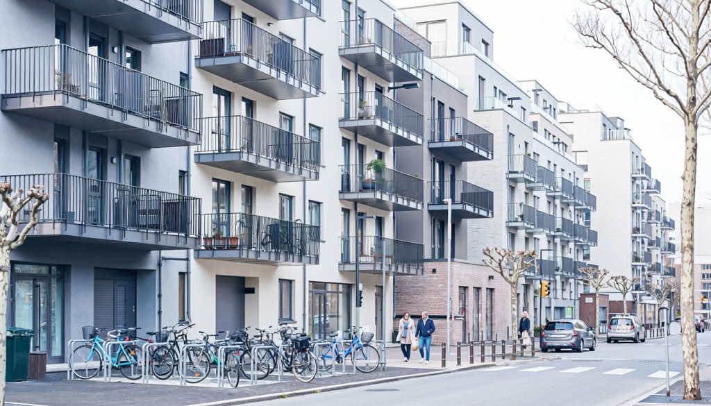 Mehrfamilienhäuser mit Balkonen in einem städtischen Wohnquartier mit Fahrrädern und Fußgängern